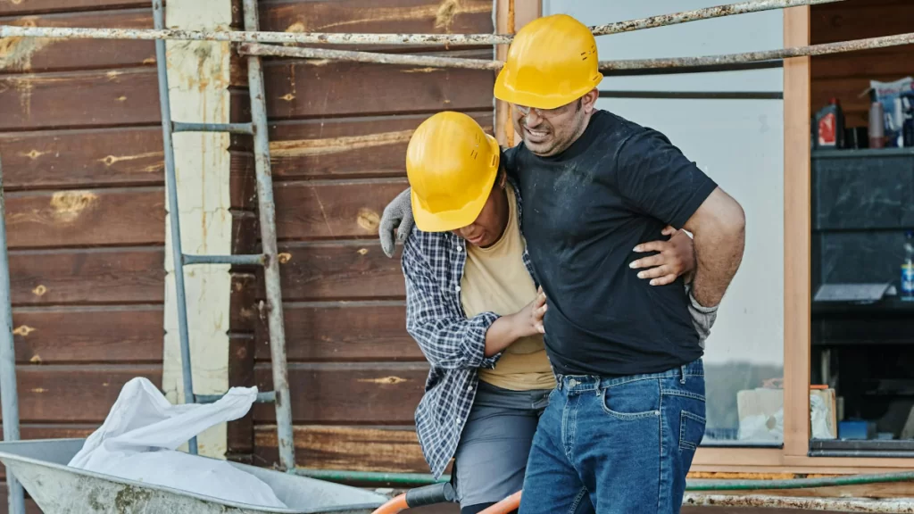 Worker helping fellow colleague after he sustained an injury on the job.